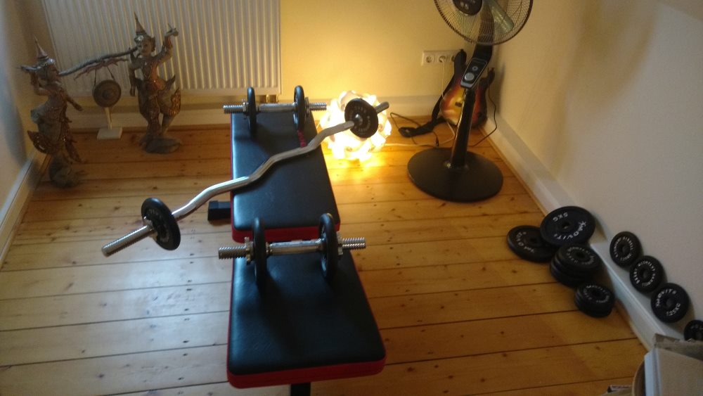 Fitnesstraining mit Hanteln und Hantelbank im Wohnzimmer